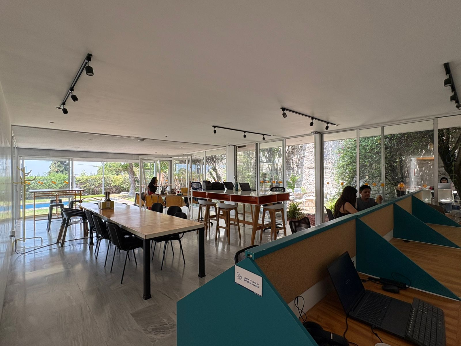 Workósfera Coworking — área abierta de escritorios, mesas comunes y vista al jardín