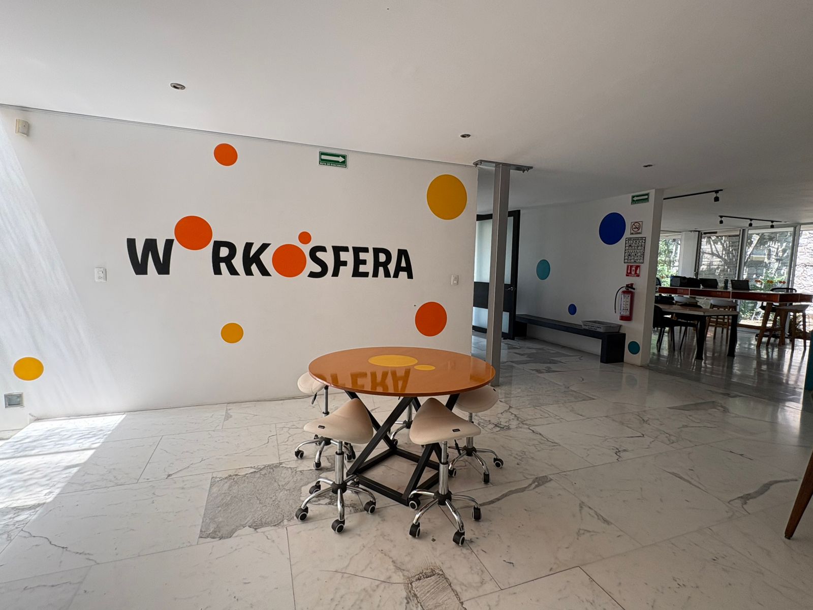 Workósfera Coworking — recepción con logo y mesa naranja en área común